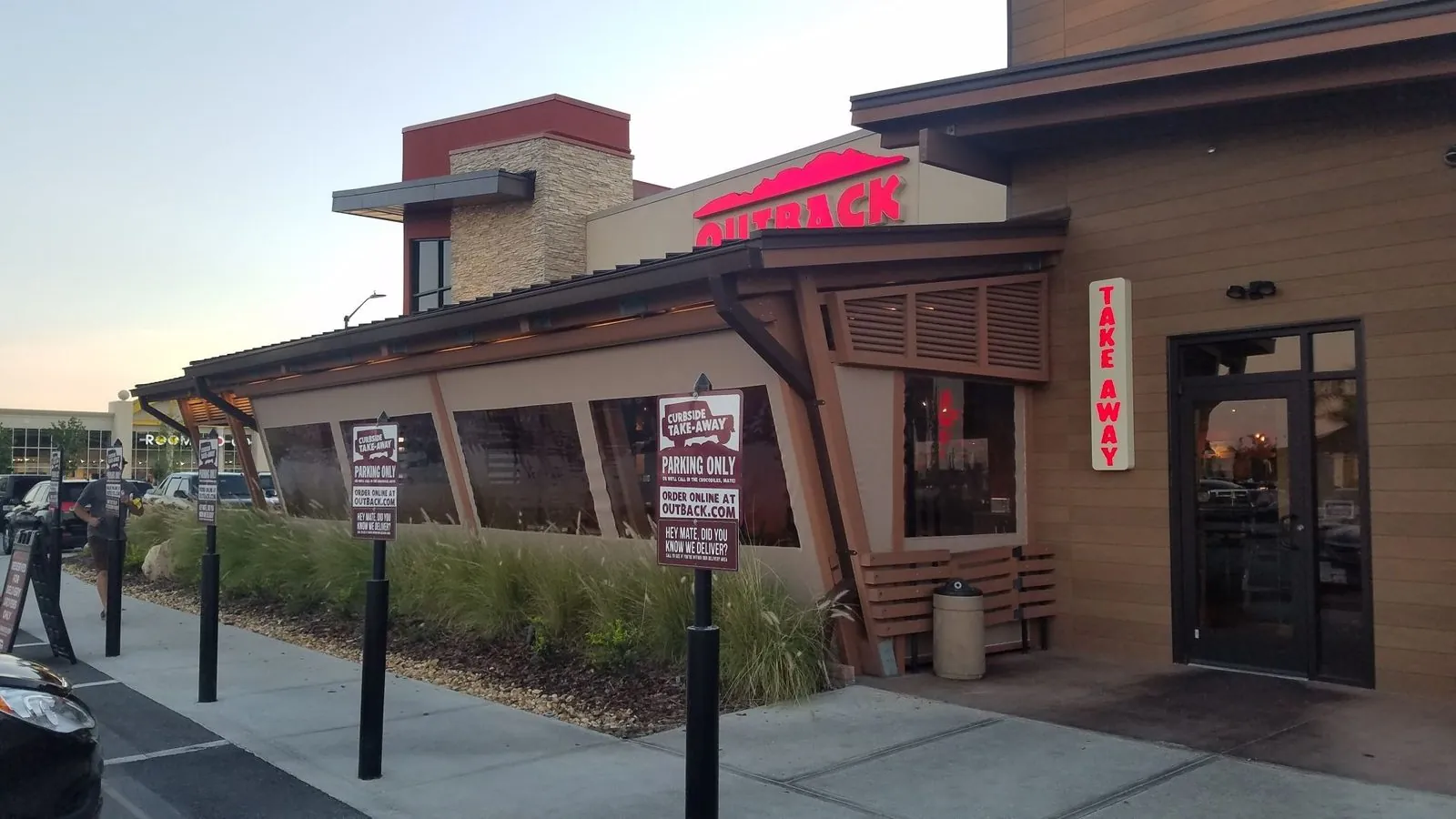 Clear vinyl screens enclosing an Outback Steakhouse patio at dusk, a MagnaTrack dealer network installation
