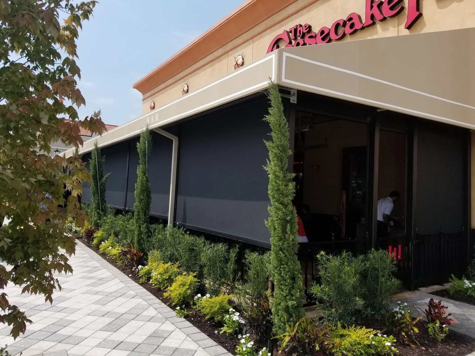 Solar screens deployed along a restaurant bar patio, a MagnaTrack dealer network installation