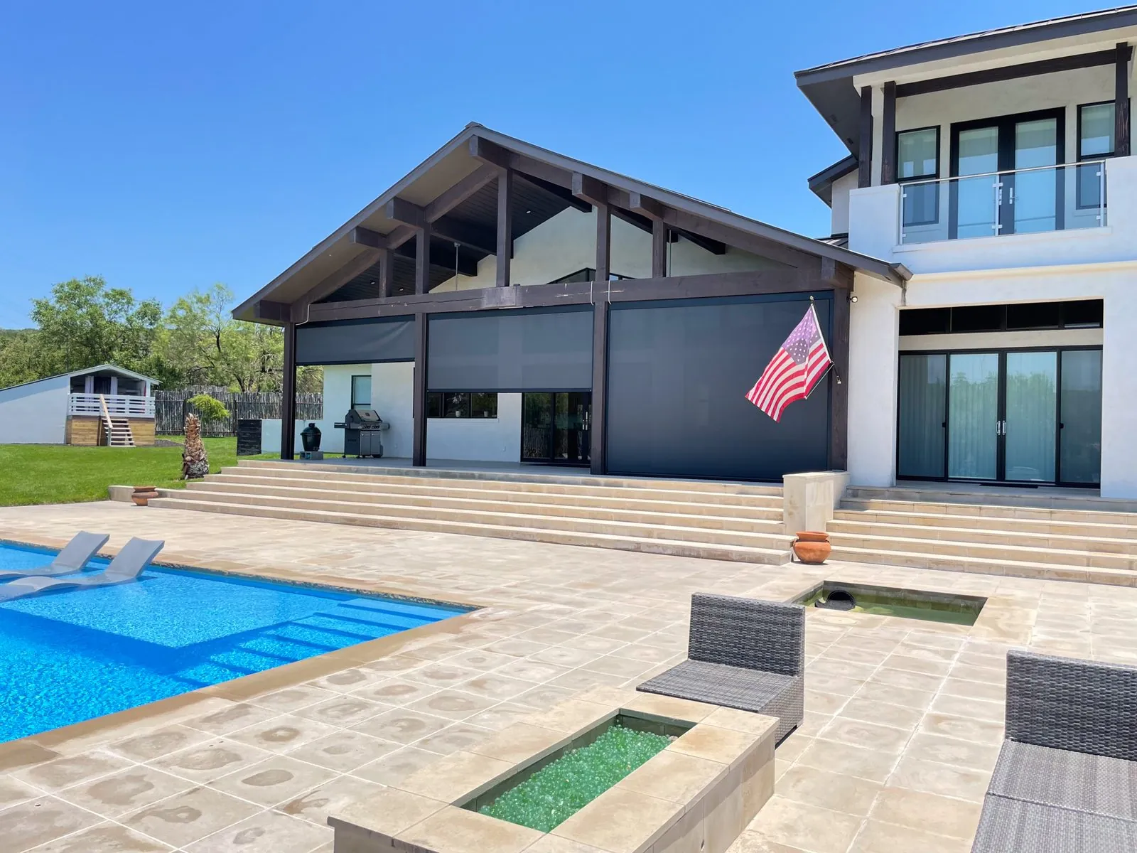 Motorized retractable screens on a modern covered patio beside a pool