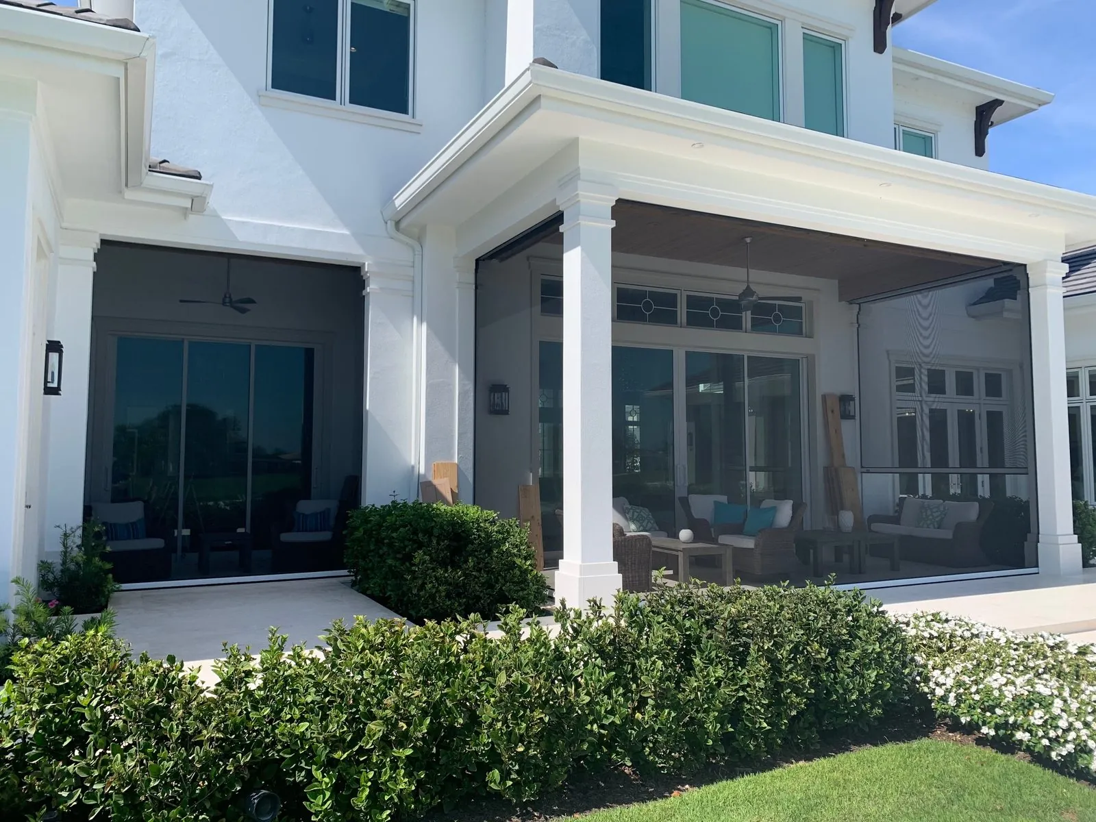 Motorized insect screens enclosing twin covered porches on a luxury white home