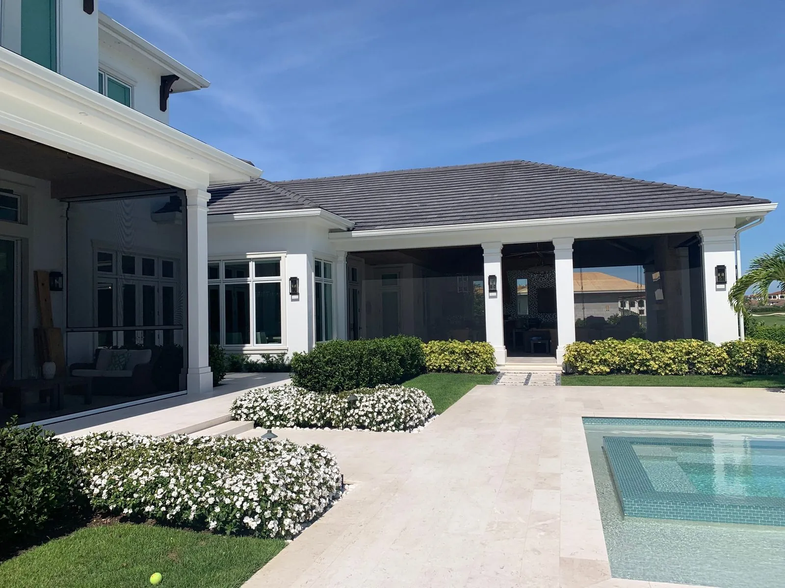 Retractable screens on a covered outdoor living area facing a pool courtyard